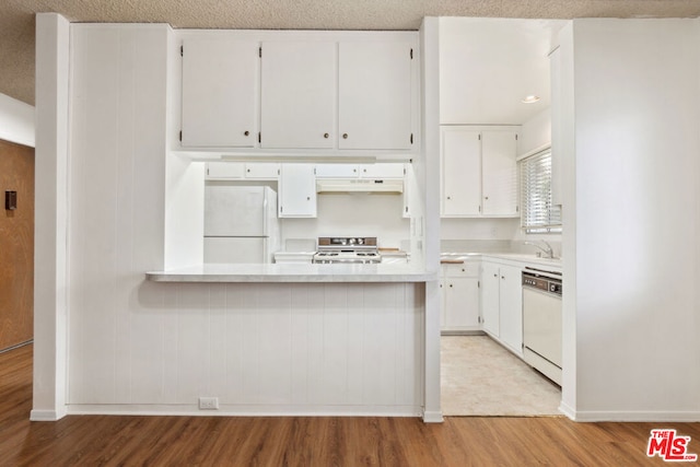 kitchen with kitchen peninsula, a textured ceiling, white appliances, white cabinets, and light hardwood / wood-style floors