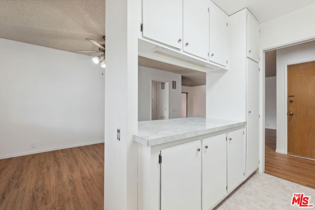 kitchen featuring a textured ceiling, white cabinetry, and light hardwood / wood-style flooring