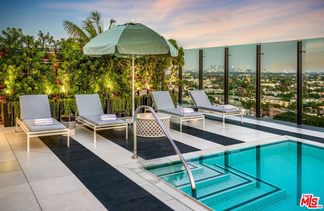 pool at dusk with an in ground hot tub and a patio area