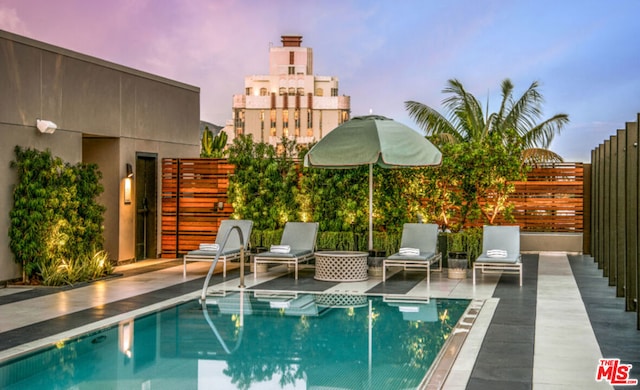 pool at dusk featuring a patio area