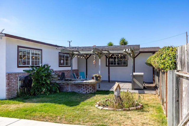 back of property with a yard, a patio area, and a pergola