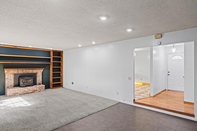 unfurnished living room with tile patterned flooring, a wood stove, and a textured ceiling