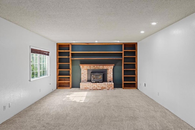 unfurnished living room featuring a wood stove, light carpet, and a textured ceiling