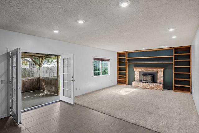 unfurnished living room featuring french doors, a textured ceiling, carpet, and a wood stove