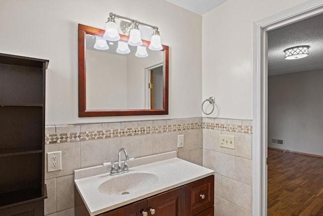 bathroom with tile walls, vanity, wood-type flooring, and a textured ceiling