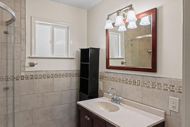 bathroom with vanity, a shower with shower door, and tile walls