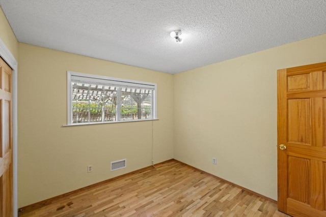 unfurnished bedroom with a closet, light hardwood / wood-style floors, and a textured ceiling