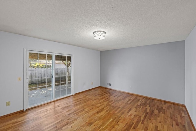 empty room with hardwood / wood-style floors and a textured ceiling