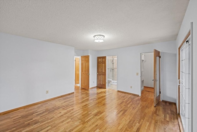 unfurnished bedroom featuring ensuite bath, a textured ceiling, and light wood-type flooring