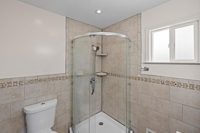 bathroom with a shower with shower door, tile walls, and toilet