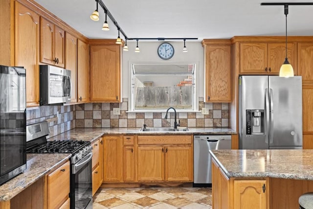 kitchen with sink, appliances with stainless steel finishes, light stone countertops, decorative backsplash, and decorative light fixtures