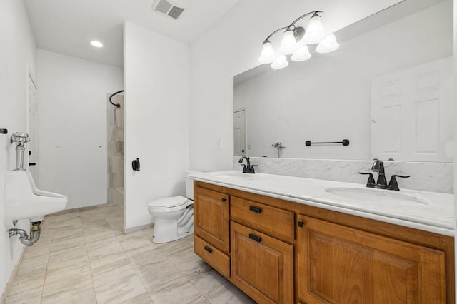 bathroom with a tile shower, vanity, and toilet