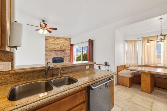 kitchen with sink, stainless steel dishwasher, ceiling fan, light stone countertops, and decorative light fixtures