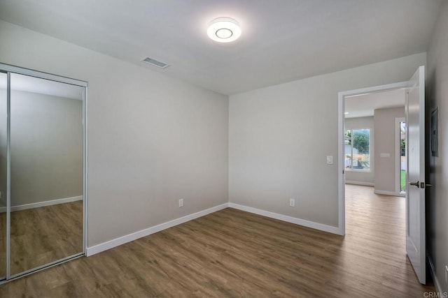 unfurnished bedroom with dark wood-type flooring and a closet