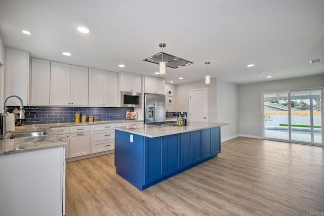 kitchen featuring pendant lighting, sink, white cabinetry, stainless steel appliances, and a center island