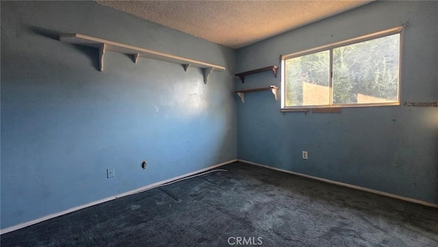 empty room featuring a textured ceiling and dark colored carpet