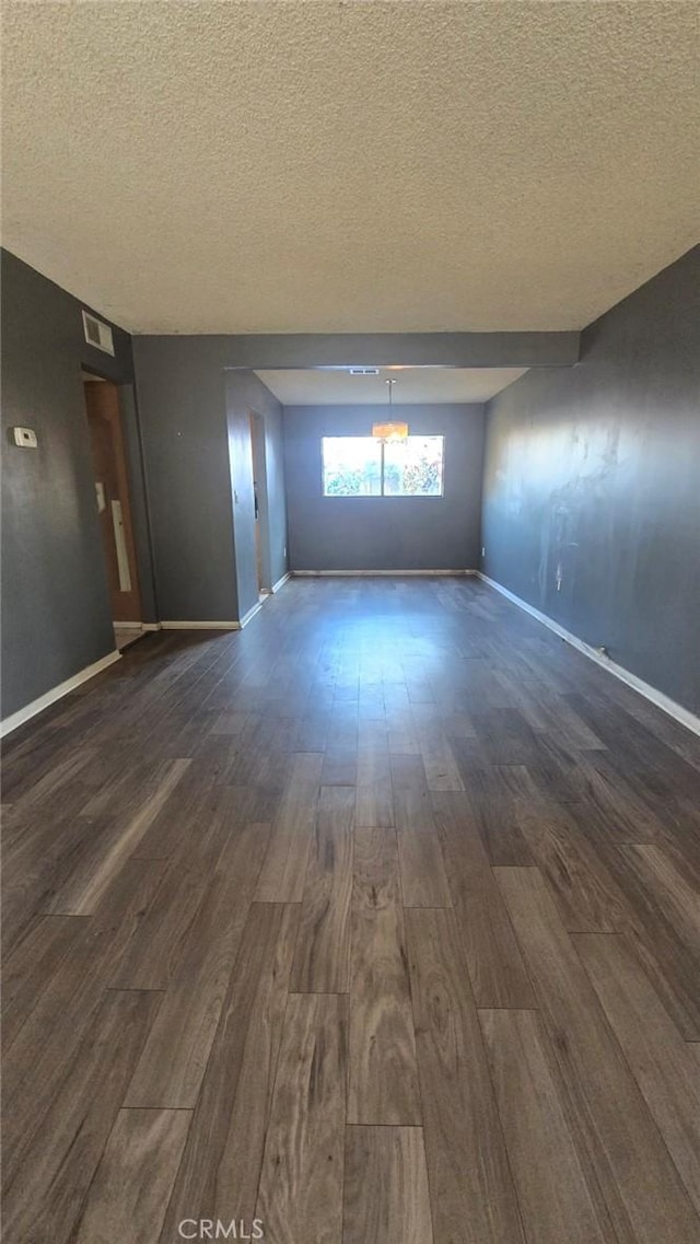 empty room with a textured ceiling and dark hardwood / wood-style floors