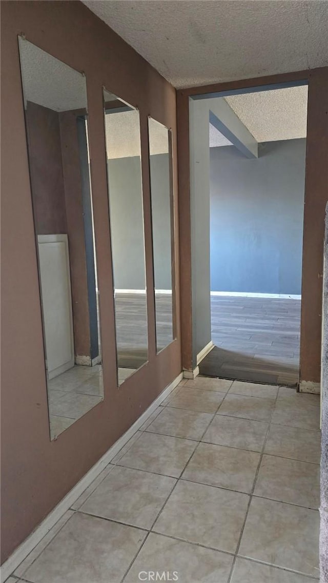 hallway with a textured ceiling and light tile patterned flooring