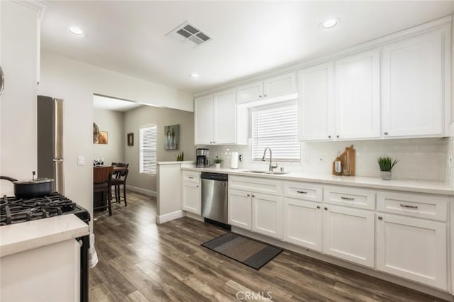 kitchen featuring white cabinetry, appliances with stainless steel finishes, backsplash, dark hardwood / wood-style flooring, and sink