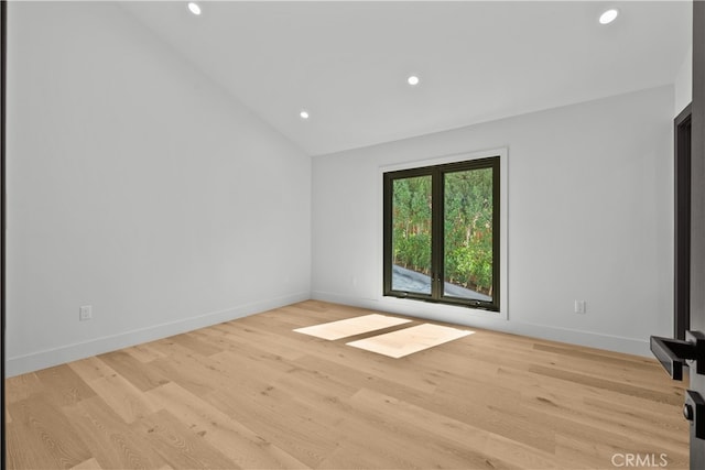 spare room featuring vaulted ceiling and light hardwood / wood-style flooring