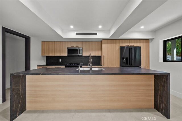 kitchen featuring light tile patterned floors, sink, kitchen peninsula, appliances with stainless steel finishes, and decorative backsplash