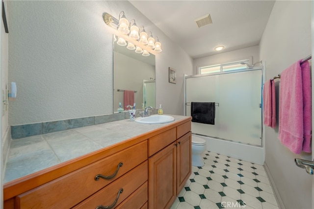 bathroom with vanity, a shower with shower door, and toilet