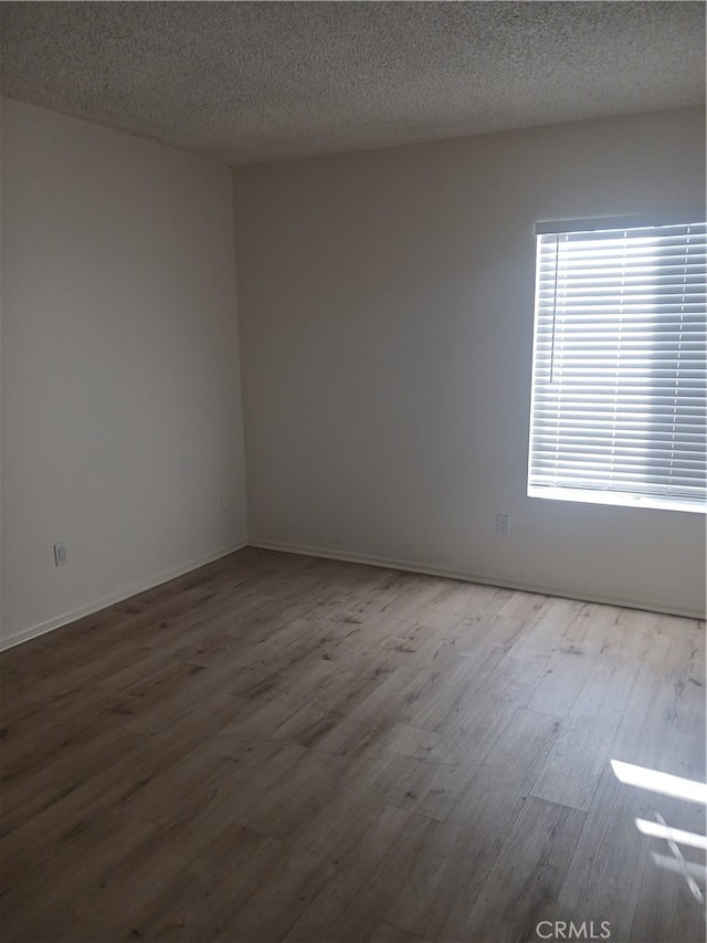 unfurnished room with hardwood / wood-style floors and a textured ceiling