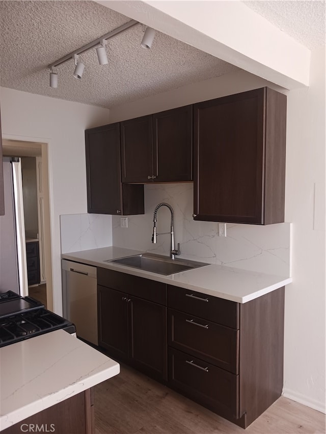 kitchen featuring sink, dark brown cabinets, rail lighting, hardwood / wood-style flooring, and appliances with stainless steel finishes