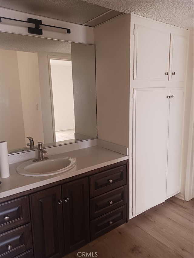 bathroom with hardwood / wood-style flooring, vanity, and a textured ceiling