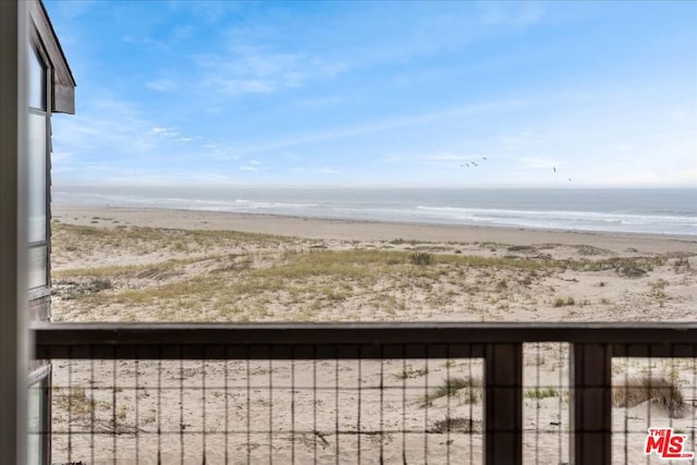 exterior space featuring a view of the beach, a water view, and a balcony