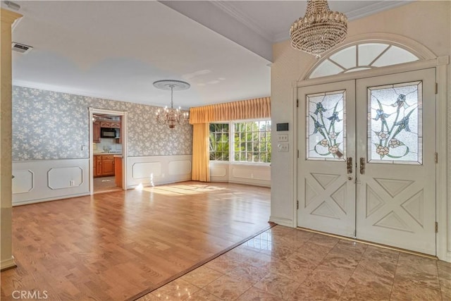 entryway featuring french doors, light hardwood / wood-style floors, an inviting chandelier, and crown molding