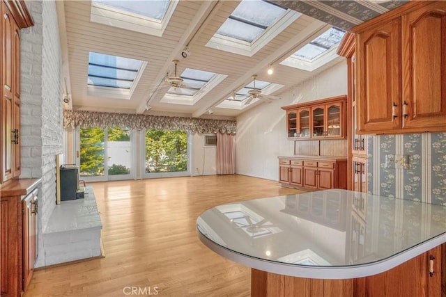 interior space featuring high vaulted ceiling, a skylight, ceiling fan, light wood-type flooring, and beamed ceiling