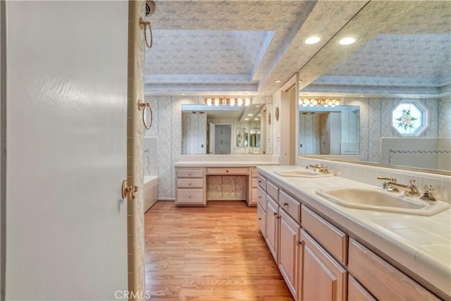 bathroom featuring hardwood / wood-style floors, vanity, a tray ceiling, and bathing tub / shower combination