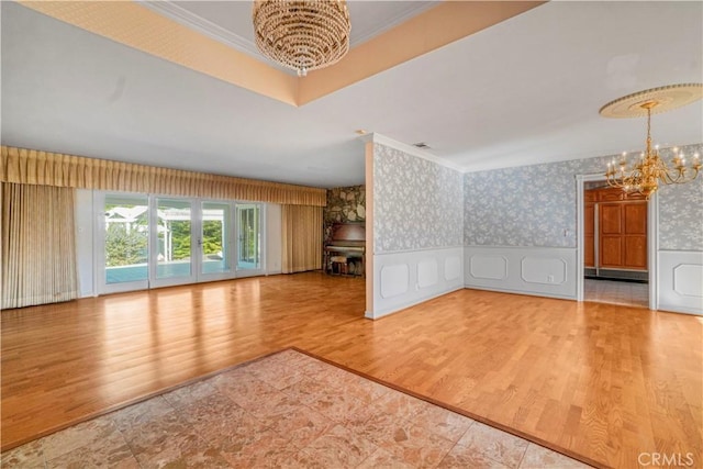 unfurnished living room featuring ornamental molding, wood-type flooring, a baseboard heating unit, and a notable chandelier