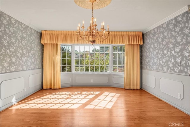 unfurnished dining area featuring hardwood / wood-style flooring, crown molding, and an inviting chandelier