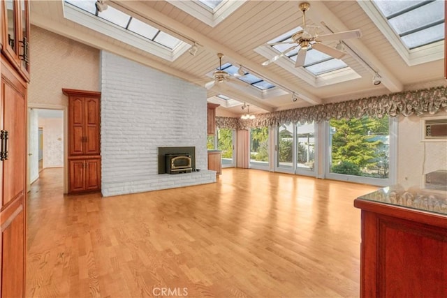 unfurnished living room with ceiling fan, high vaulted ceiling, beamed ceiling, light hardwood / wood-style floors, and a wood stove