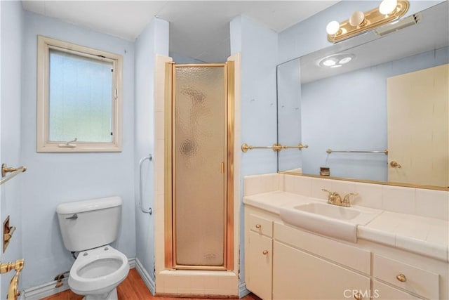 bathroom featuring wood-type flooring, vanity, toilet, and a shower with shower door