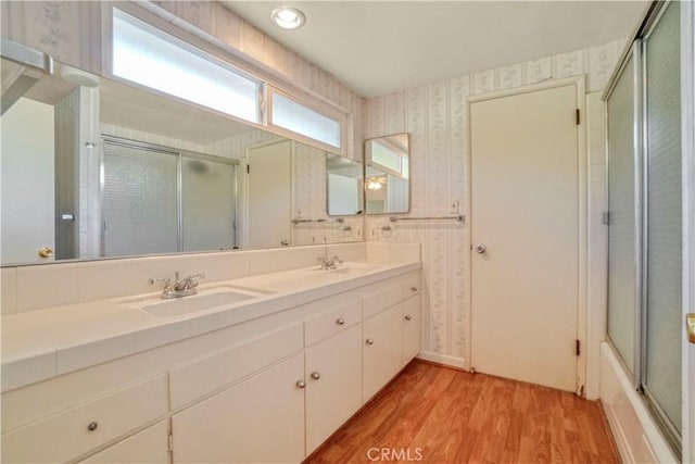 bathroom featuring combined bath / shower with glass door, wood-type flooring, and vanity