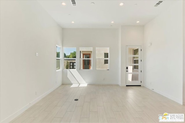 empty room featuring light wood-type flooring and a high ceiling