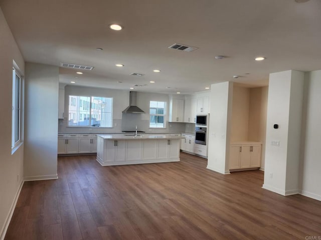 kitchen featuring white cabinets, wall chimney exhaust hood, visible vents, and built in microwave