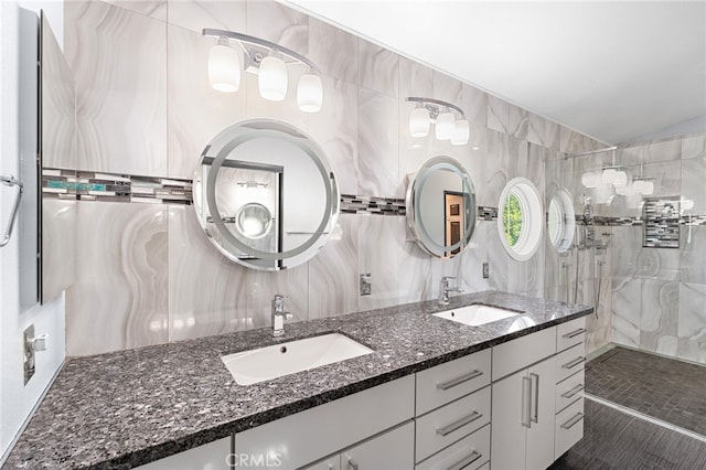 bathroom with tile patterned flooring, tiled shower, tile walls, backsplash, and vanity