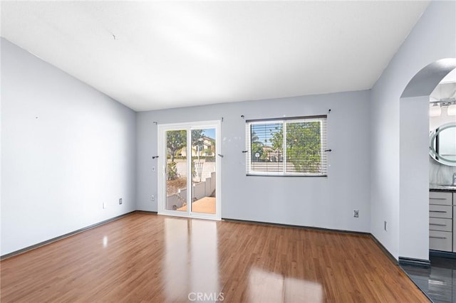 20664 Brana Rd, Riverside, CA 92508 - unfurnished living room with wood finished floors, arched walkways, a sink, and baseboards