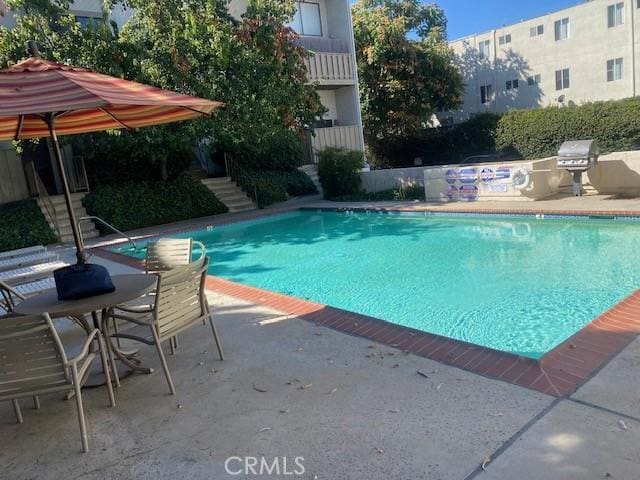 view of swimming pool with an outdoor kitchen and a patio area