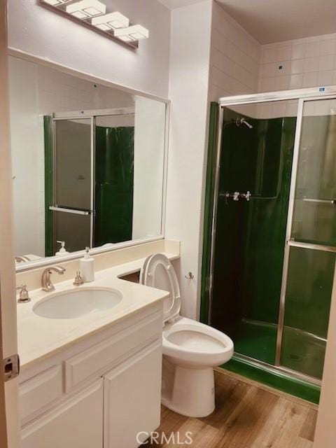 bathroom with vanity, toilet, hardwood / wood-style flooring, and a shower with door