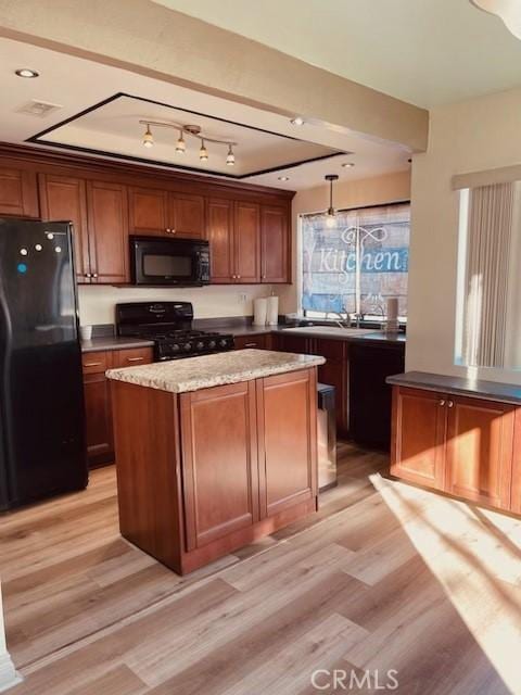 kitchen featuring sink, light wood-type flooring, black appliances, and a kitchen island