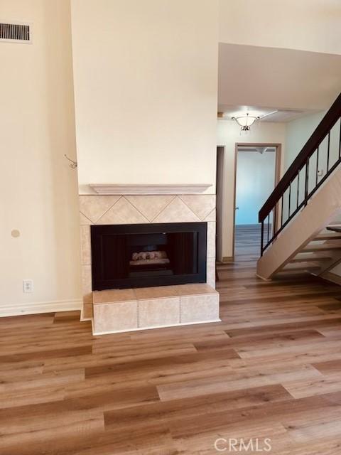 unfurnished living room featuring hardwood / wood-style floors and a tile fireplace