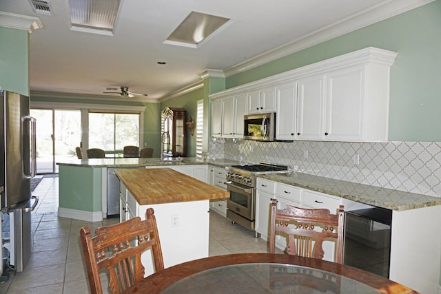 kitchen with kitchen peninsula, ceiling fan, white cabinetry, ornamental molding, and stainless steel appliances