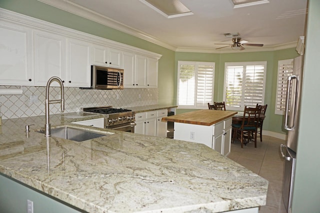 kitchen with wooden counters, decorative backsplash, kitchen peninsula, white cabinetry, and appliances with stainless steel finishes