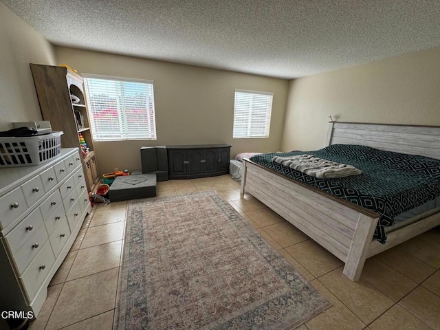 bedroom featuring a textured ceiling, light tile patterned flooring, and multiple windows