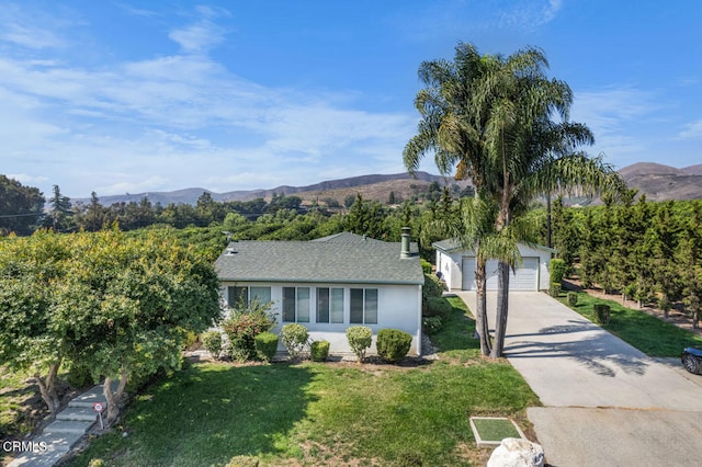 ranch-style house featuring a garage, a mountain view, an outbuilding, and a front lawn